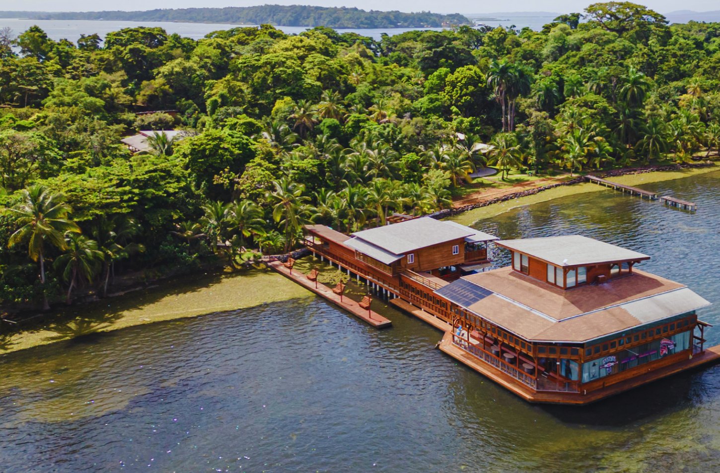 Aerial view of a stilt house over the water at the edge of a forested island