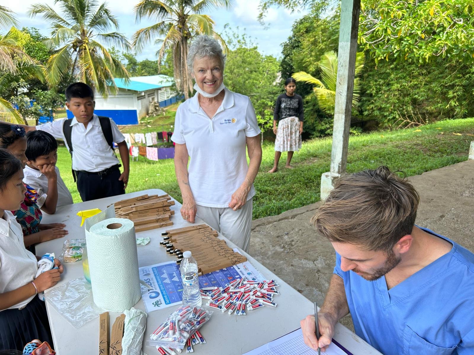 Volunteers at an outdoor table with toothbrushes and supplies for schoolchildren
